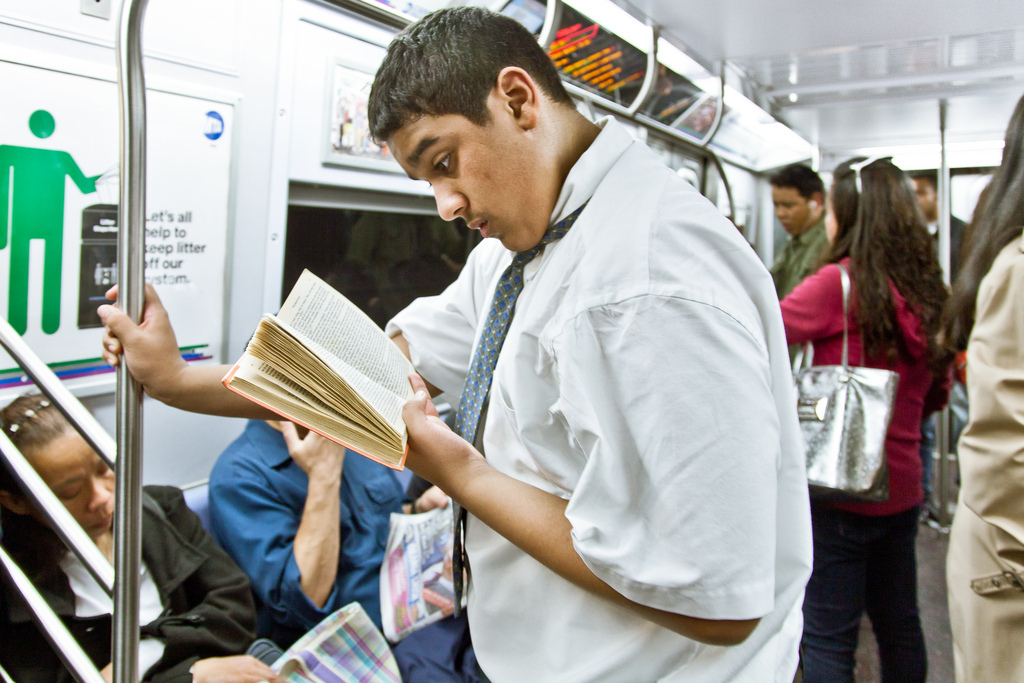 Она читает в метро. Парень читает книгу в метро. Читает на ходу. Человек читает книгу на ходу. Чтение в странных местах.